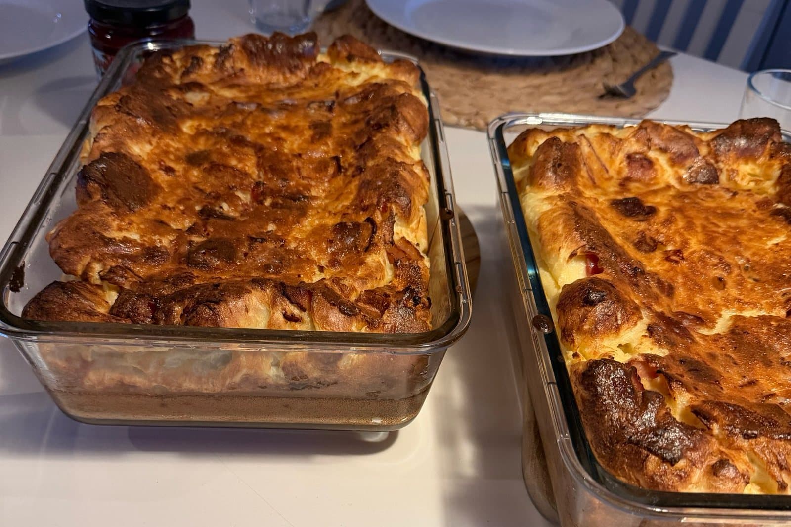 Två glasformar på ett dukat bord. Ytan har svällt upp över formkanterna och är gyllenbrun med mörkare bitar i.