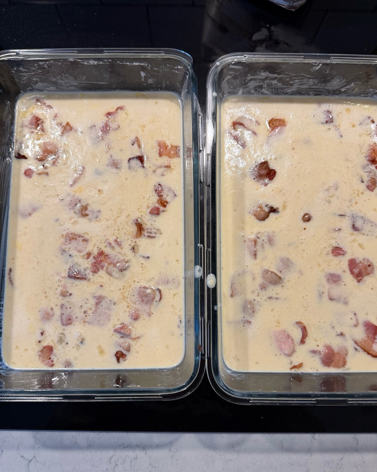 Två glasformar fyllda med ljus smet där baconbitarna ligger utspridda i ytan.